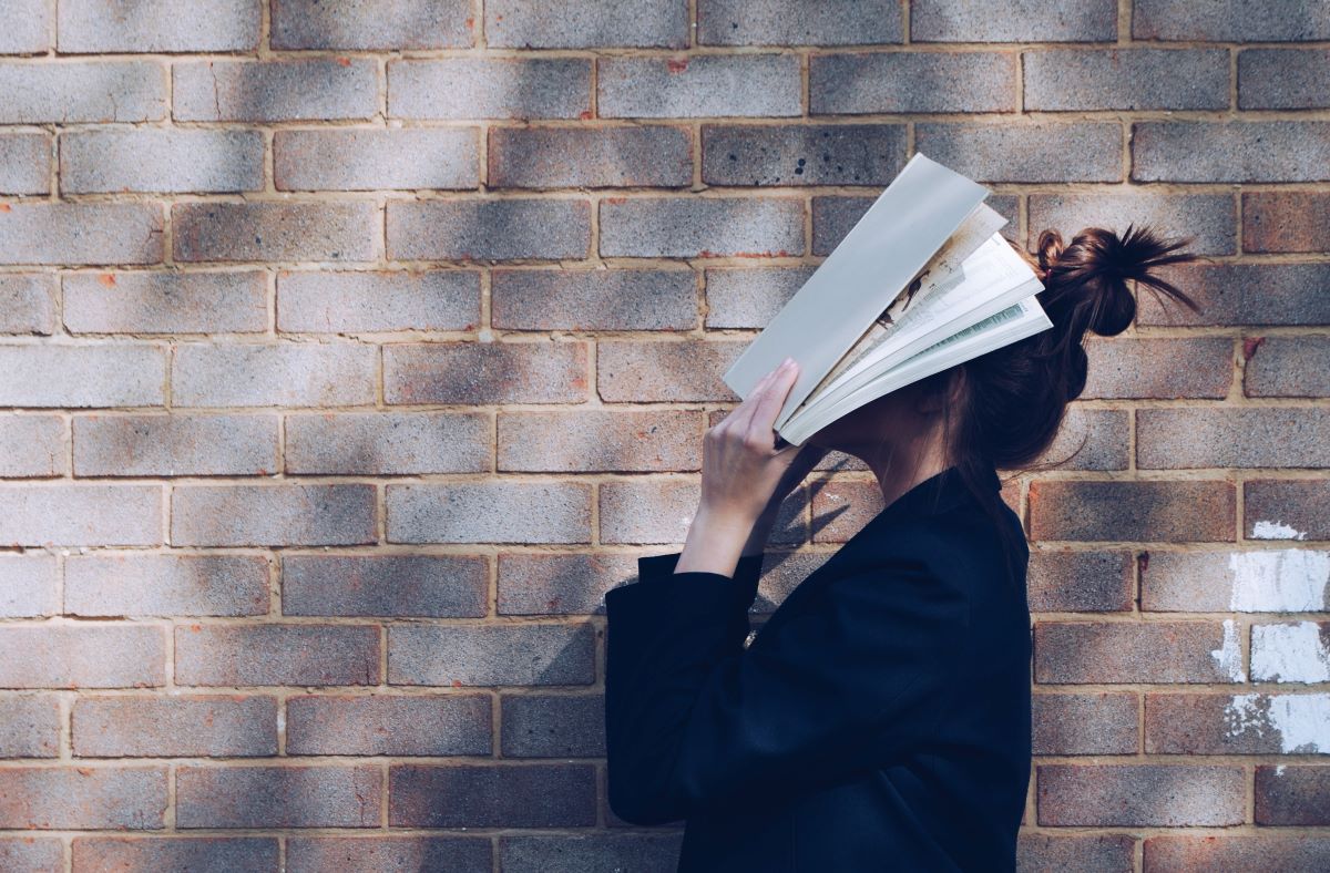 woman covering face while reading